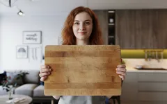 Vrouw houdt houten snijplank vast in moderne keuken